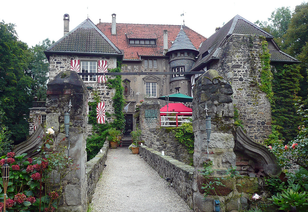 Der Zugang zur Burg Lede (Hintergrund) über die Burggraben-Brücke (Vordergrund) (2014)
