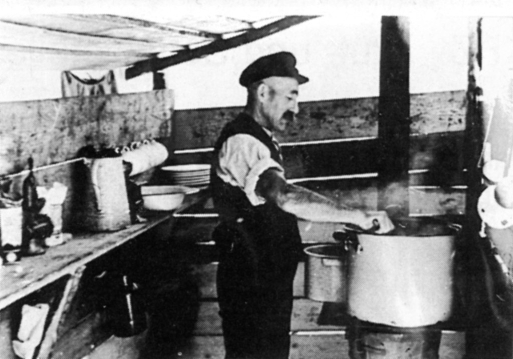 Der Koch bereitet in seiner provisorischen Küche das Essen für die Flößer (um 1910)