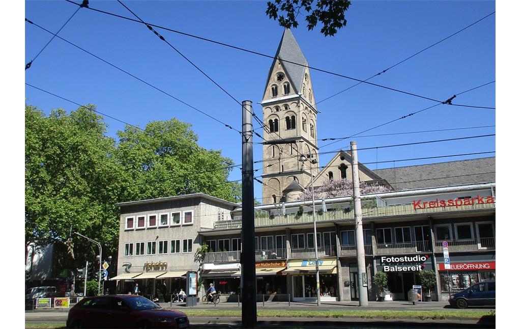 Das Café und Restaurant "Riphahn" (links) und benachbarte Geschäftsgebäude in der Hahnenstraße in Köln-Altstadt-Süd, dahinter der Turm der Kirche des Kollegiatstifts Sankt Aposteln in Altstadt-Nord (2019).