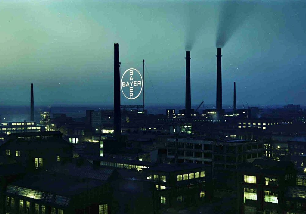 Nachtaufnahme vom Bayer-Werk Leverkusen, im Hintergrund das beleuchtete Bayer-Kreuz (fotografiert vom Dach des Kraftwerks Y 9, 1958).