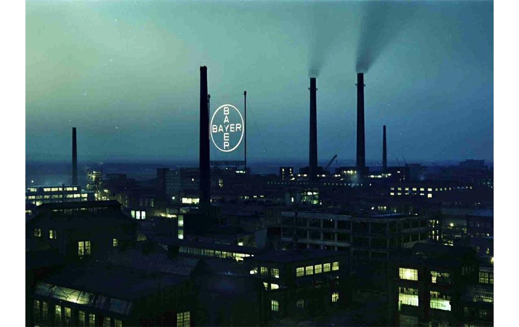 Nachtaufnahme vom Bayer-Werk Leverkusen, im Hintergrund das beleuchtete Bayer-Kreuz (fotografiert vom Dach des Kraftwerks Y 9, 1958).