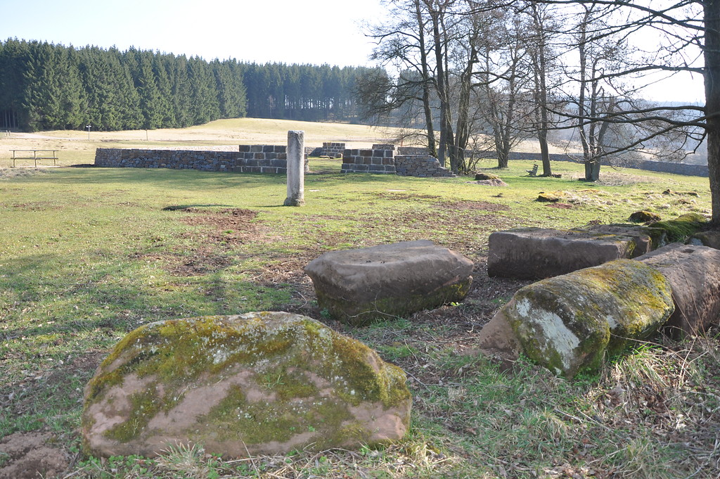 Blick auf das römische Kleinkastell in Nettersheim. Im Vordergrund lose liegende, vor Ort gefundene Bausteine und eine wieder aufgerichtete Säule (2014)