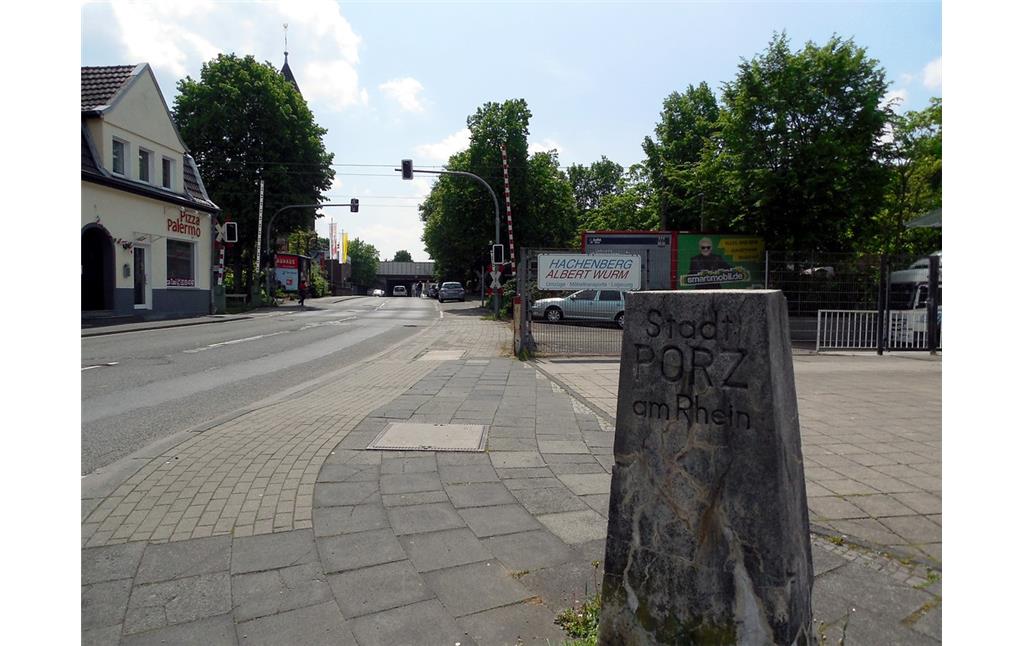 Die Eiler Straße in Köln-Porz mit Blickrichtung zur Autobahnbrücke der A 3 mit dem Grenzstein der ehemaligen Stadt Porz (2015)