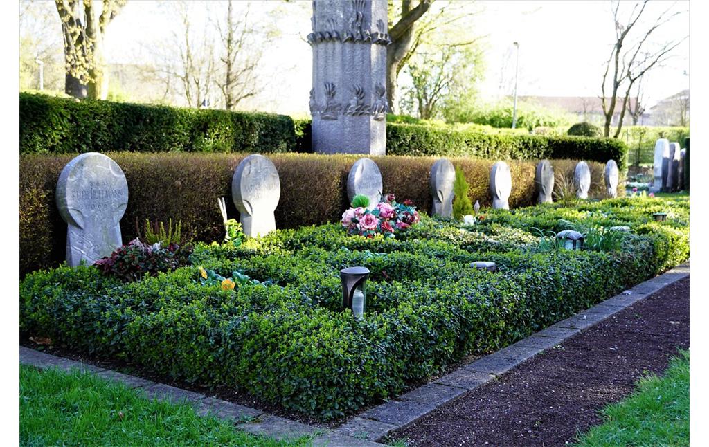 Gemeinsame Grabstätte der Schulkinder, die bei dem Flammenwerfer-Attentat von Köln-Volkhoven getötet wurden, auf dem Friedhof in Volkhoven/Weiler, Blick von Südosten auf die acht einfachen Grabkreuze und die gepflegte Grabanlage (2023).