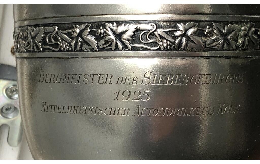 Pokal zum Motorradrennen "Goldener Kranz des Siebengebirges" am 26. April 1925 aus dem Bestand des Siebengebirgsmuseum Königswinter (Inventar-Nr. 2018-FH-0080, Aufnahme 2023). Die Aufschrift lautet: "Bergmeister des Siebengebirge / 1925 / Mittelrheinischer Automobilklub Köln".