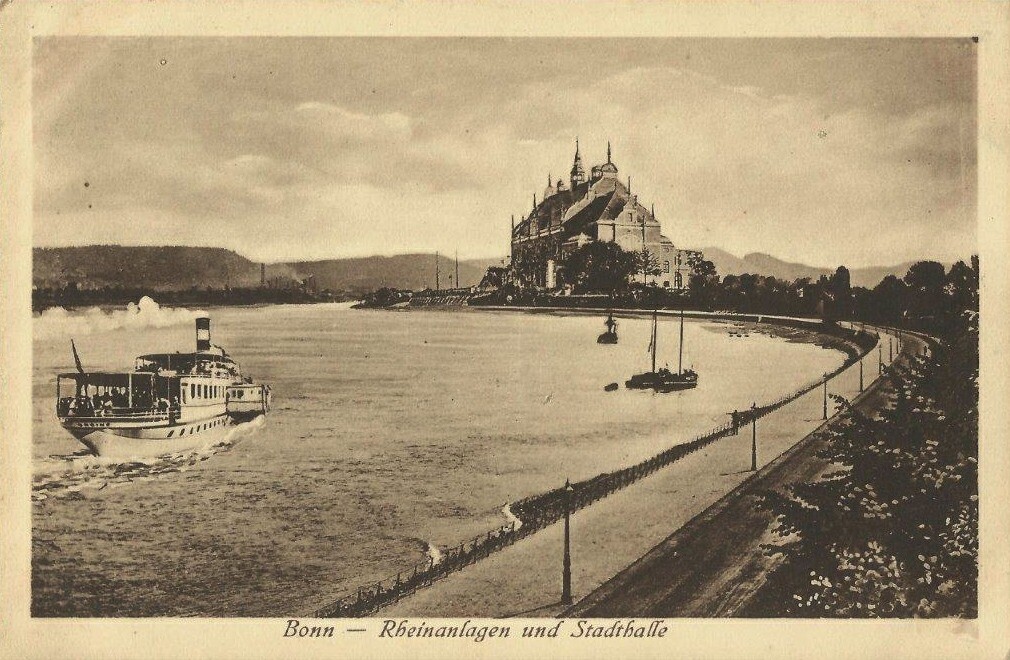 Auf das Jahr 1920 datierte Postkarte "Bonn - Rheinanlagen und Stadthalle". Vor der später im Zweiten Weltkrieg zerstörten Stadthalle schippert ein dampfbetriebenes Ausflugsschiff auf dem Rhein.