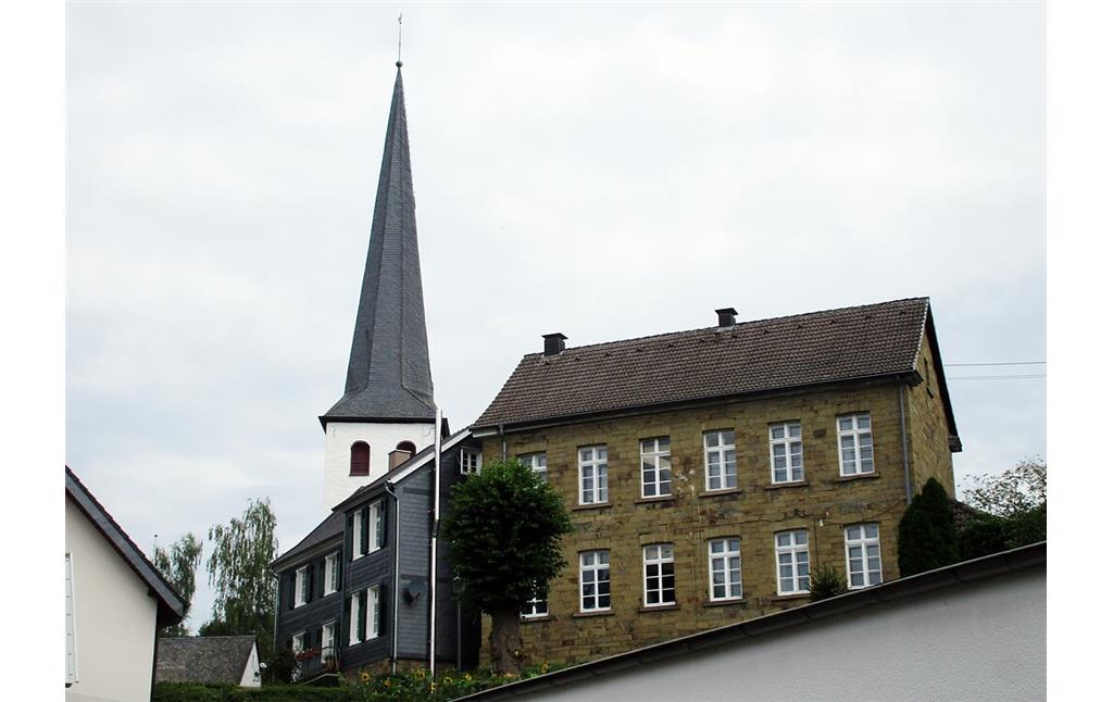 Blick von der Burgstraße aus auf ältere Wohnhäuser und die evangelische Kirche in Ruppichteroth (2021).
