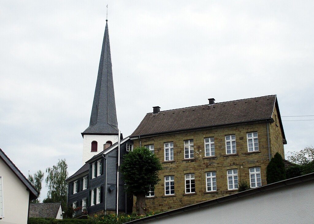 Blick von der Burgstraße aus auf ältere Wohnhäuser und die evangelische Kirche in Ruppichteroth (2021).