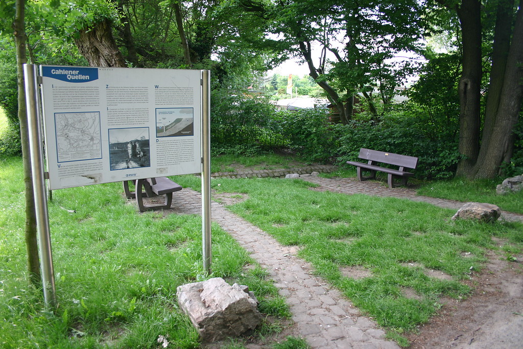 Informationstafel vor einem kleinen Platz mit Sitzbänken (2008). Die Überschrift der Tafel lautet "Gahlener Quellen".