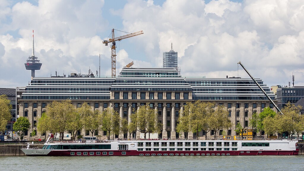 Die "Neue Direktion Köln", die alte Reichsbahndirektion am Kölner Rheinufer, nach dem erfolgtem Umbau, nun mit drei zusätzlichen Staffelgeschossen (Mai 2016). Am Ufer liegt das Flusskreuzfahrtschiff "Sound of Music".