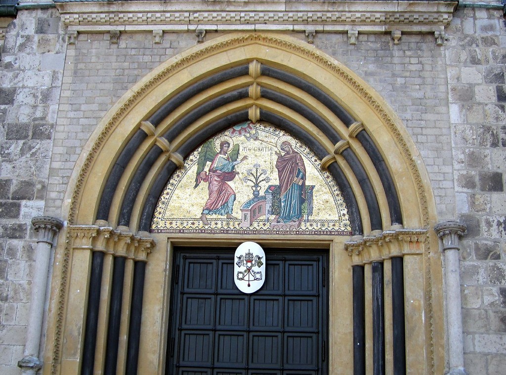 Portal an der Nordseite des Kirchengebäudes des Cassiusstifts (Münster in Bonn, 2011). Zentral am Portal wird auf einer Wappentafel der Ehrentitel einer "Basilica minor" ("kleinere Basilika") ausgewiesen.
