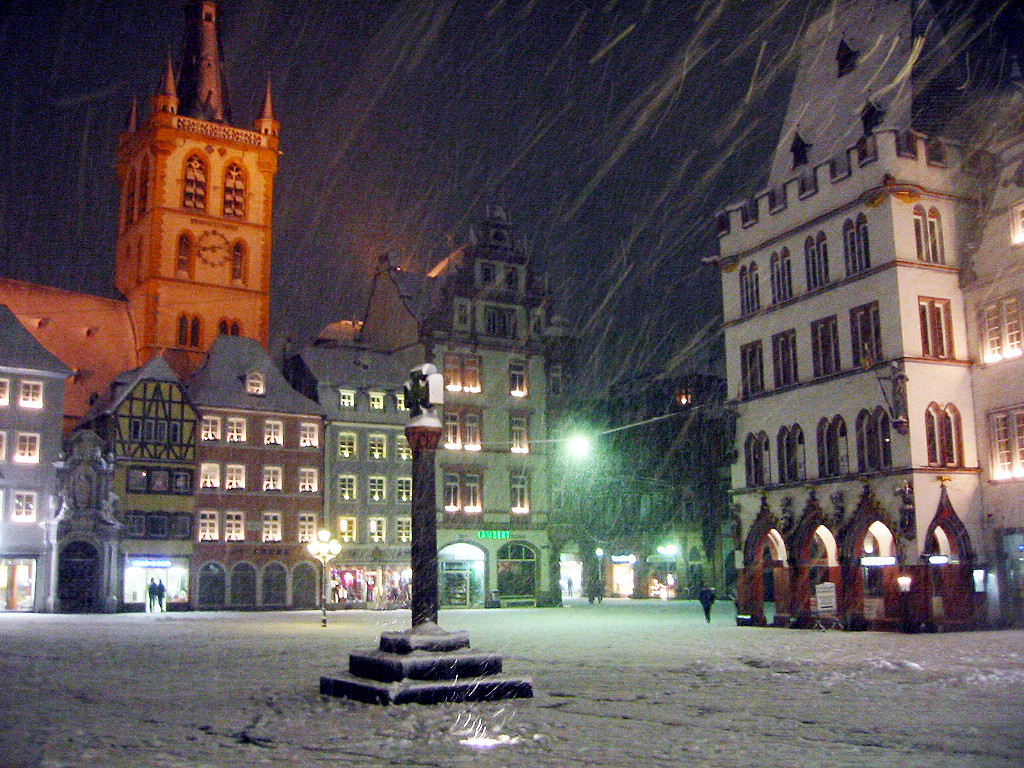 Der Trierer Hauptmarkt mit dem mittelalterlichen Marktkreuz (heute eine Kopie) im abendlichen Schneetreiben; links die Marktkirche St. Gangolf, rechts das gotische Gebäude 'Steipe' (2004)