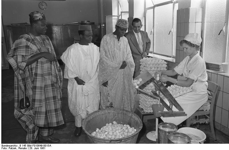 Historische Aufnahme von 1961: Eine Parlaments-Delegation aus der Republik Niger bei der Besichtigung der Firma "Verpoorten" in Bonn, rechts im Bild eine Mitarbeiterin beim Aufschlagen von Eiern.