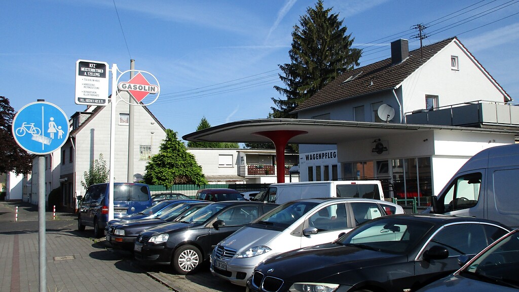 Die an der Hauptstraße in Troisdorf-Spich gelegene frühere Tankstelle (2022), heute als Autowerkstatt mit Gebrauchtwagenhandel und Wagenpflege genutzt.