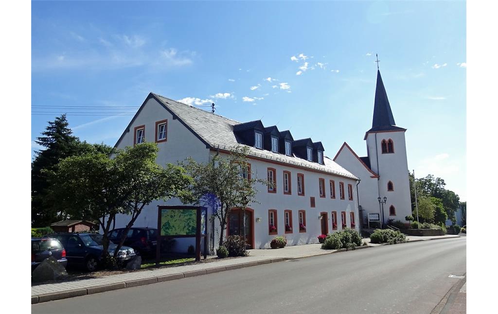 Das Gemeindehaus und dahinter die katholische Pfarrkirche St. Luzia in Habscheid im Eifelkreis Bitburg-Prüm.
