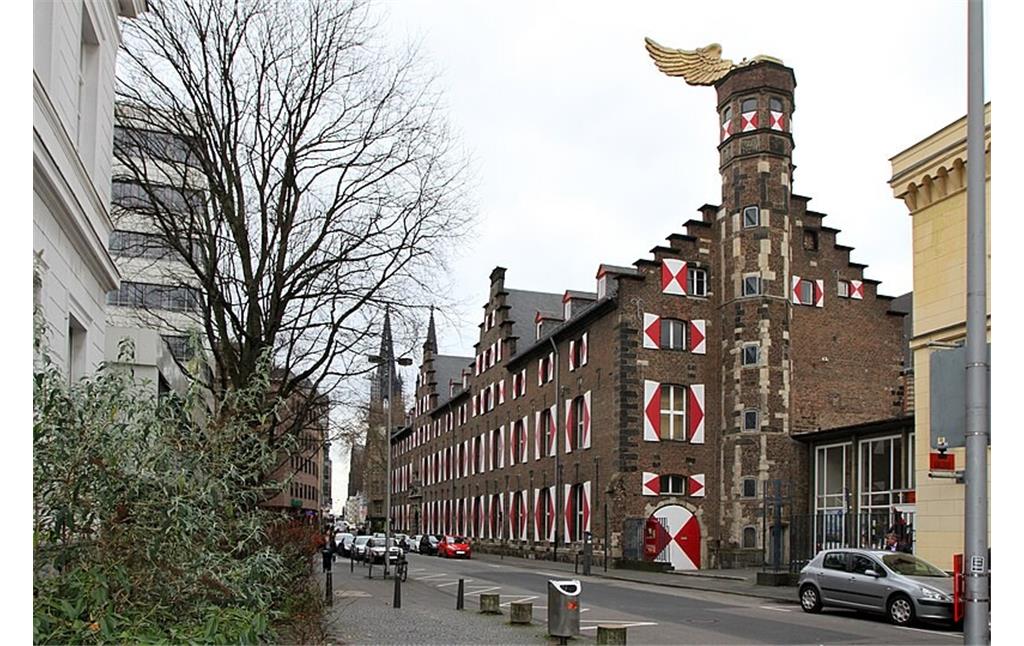 Das Zeughaus in Köln mit historischem Treppenturm und dem darauf befestigten Kunstwerk "Goldener Vogel" von HA Schult (2012). Rechts im Bild ist ein Teil der Alten Wache zu erkennen.
