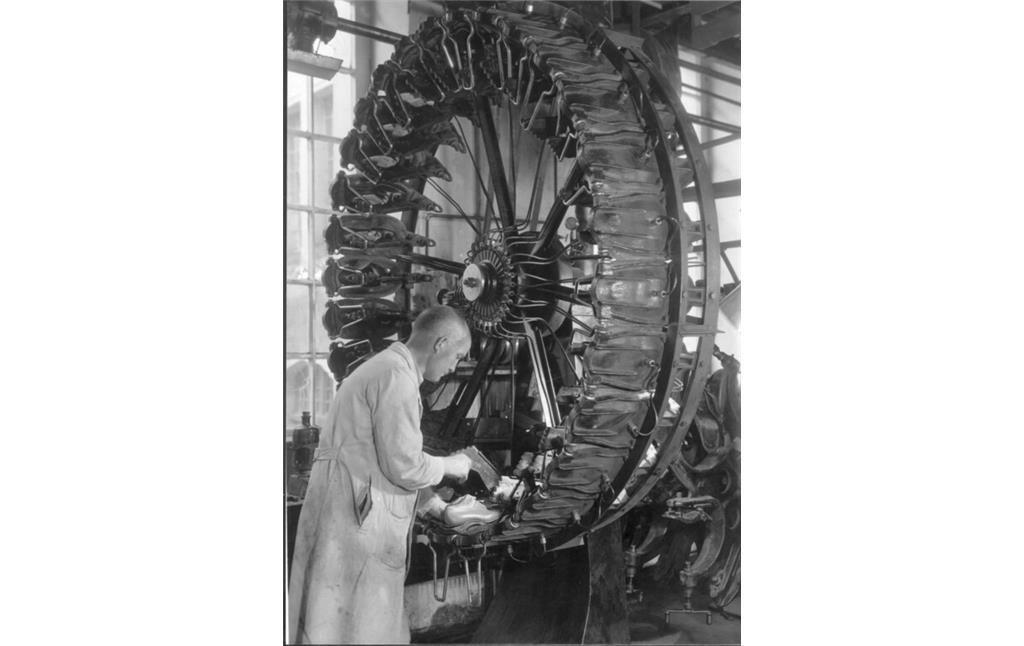 Ein Arbeiter der Rheinberger AG in Pirmasens bedient die Radpresse für die Herstellung von Sohlen (1930er/1940er Jahre)