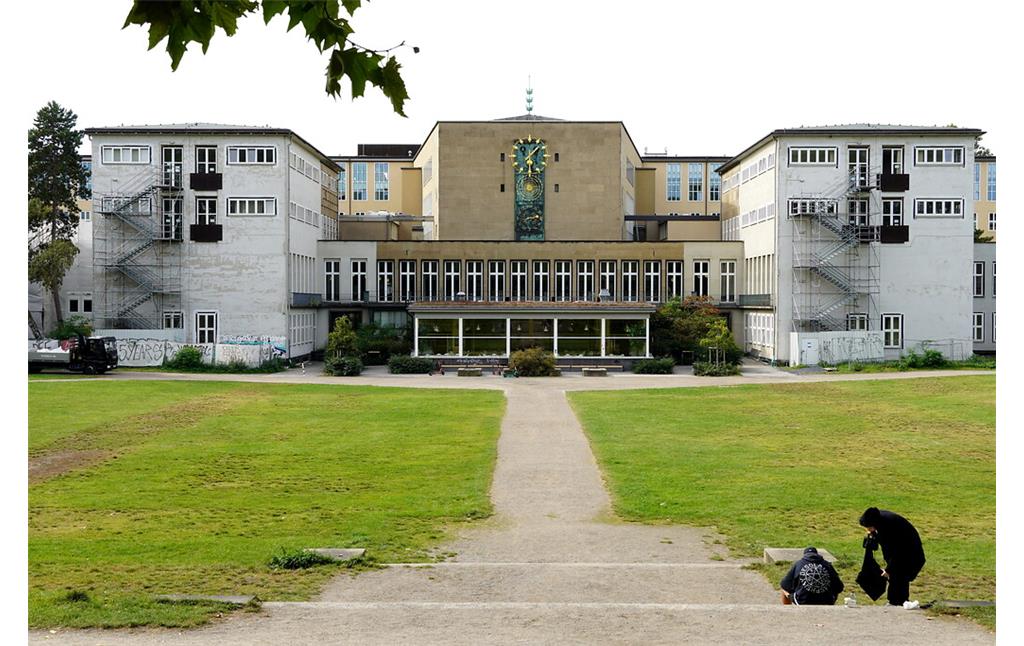 Rückwärtige Ansicht des Hauptgebäudes der Universität zu Köln in Lindenthal über die Uniwiesen hinweg (2021). Im Sommer werden die Wiesen von den Studierenden für Freizeit, Sport und Pausen genutzt.