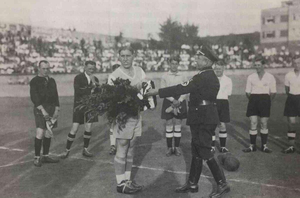 Ein Offizieller in NS-Uniform begrüßt den Mannschaftskapitän des FC Schalke 04, Ernst Kuzorra (1905-1990), vor dem Fußballspiel zwischen der Mannschaft der TuRa Bonn und dem FC Schalke 04.
