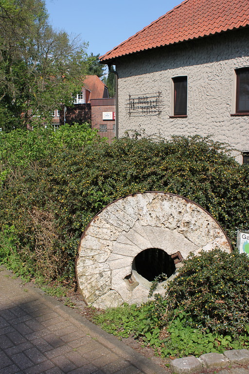 Alter Mühlstein, der an der Gahlener Mühle aufgestellt wurde. Im Hintergrund steht das Mühlengebäude (2014).