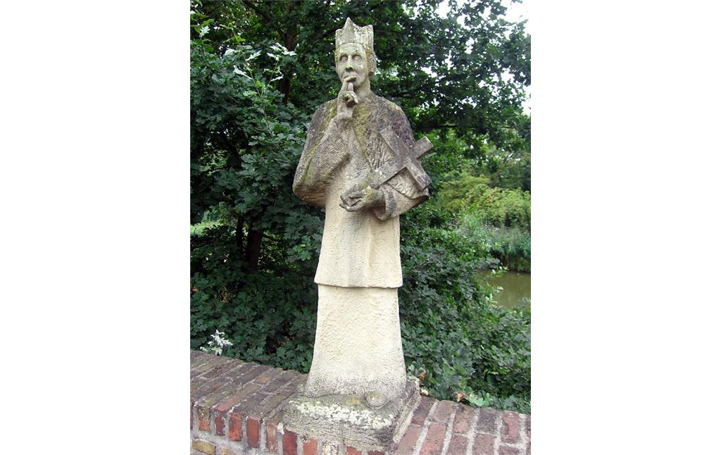 Figur des Heiligen Johannes Nepomuk auf dem  Übergang über die Gräfte von Schloss Bachem bei Frechen (2013). Der Brückenheilige ist wie üblich mit einem Kreuz in der einen Hand und der anderen Hand vor dem Mund dargestellt.