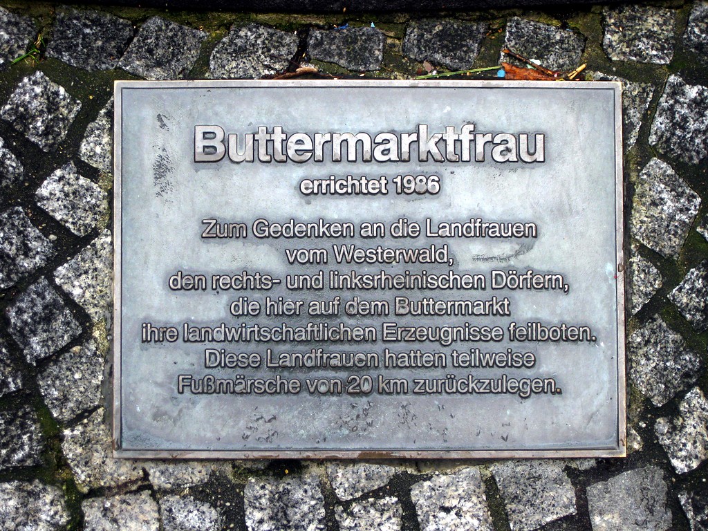 Hinweistafel "Buttermarktfrau" am Brunnen mit der Landfrau Agnes auf dem Marktplatz "Buttermarkt" in Linz am Rhein (2015).