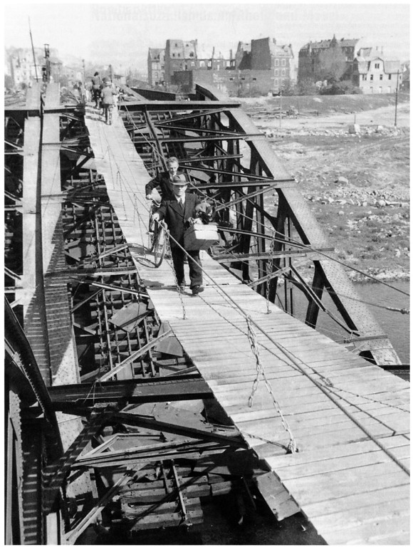 Koblenzer Einwohner passieren am 26. April 1945 die vom 372. Pionier-Regiment der US-Armee über der schwer beschädigten Moseleisenbahnbrücke errichtete Hängebrücke.